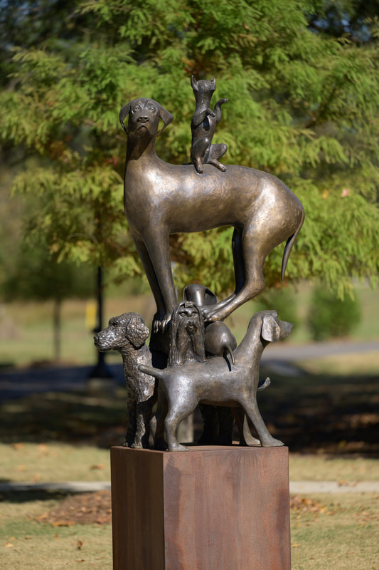 "Dogs Dogs Dogs" is a bronze sculpture displayed at Northern Riverwalk submitted by Birmingham Sculpture to City of Tuscaloosa Public Art Committee.